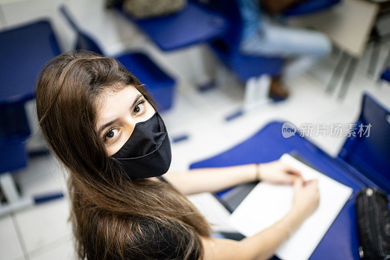 一个大学/高中学生戴着口罩在教室里的肖像